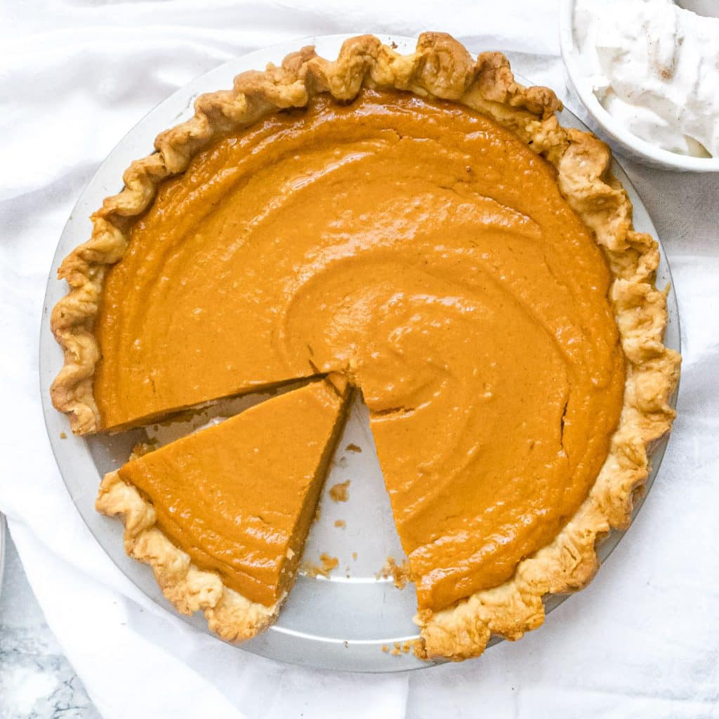 Overhead shot of brown butter sweet potato pie with a slice cut out and whipped cream on the side