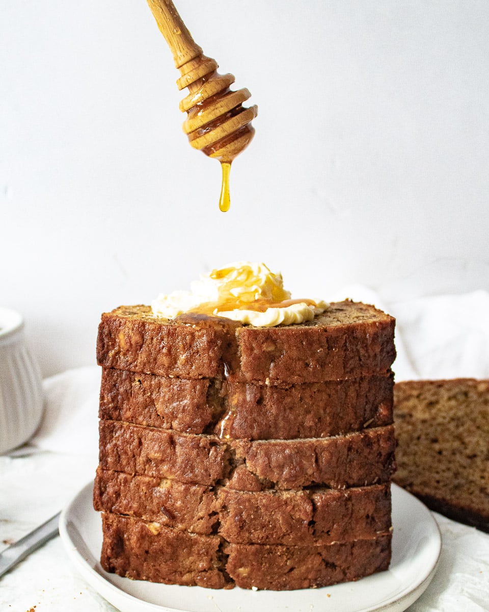 stacked pineapple banana bread with butter and a honey dripper drizzling honey on top