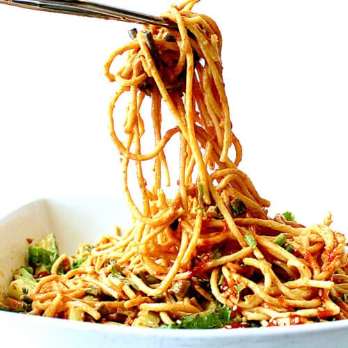 tongs serving peanut noodle salad from a bowl