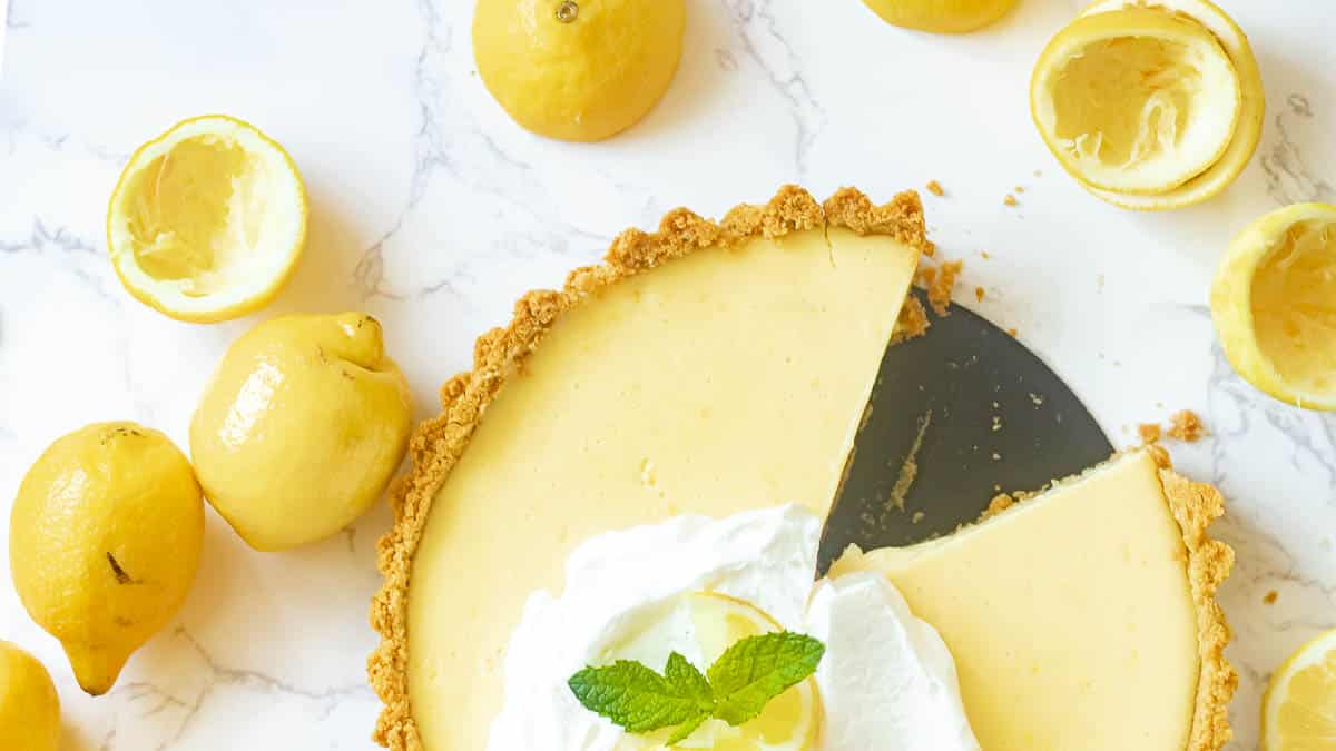 lemon icebox pie with slices cut out and lemons surrounding