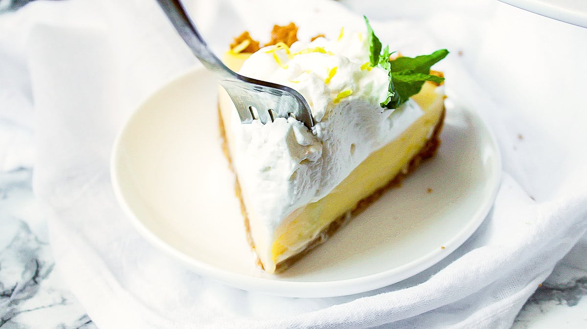 lemon icebox pie on a plate with a fork cutting into it