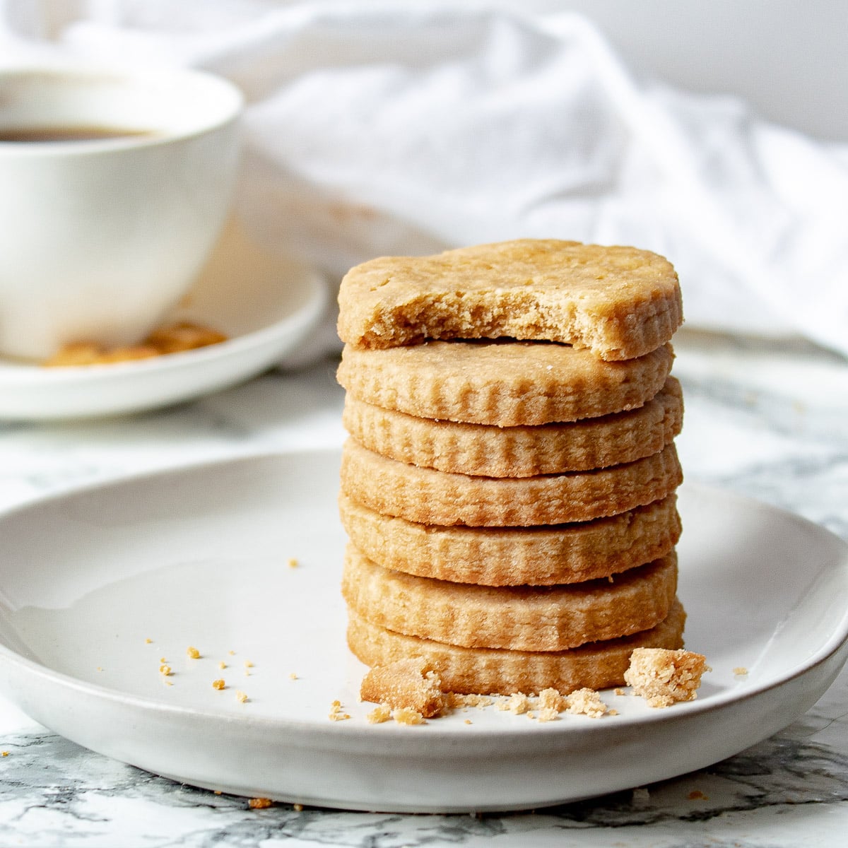 stack of brown sugar shortbread cookies with a cup of coffee in the background