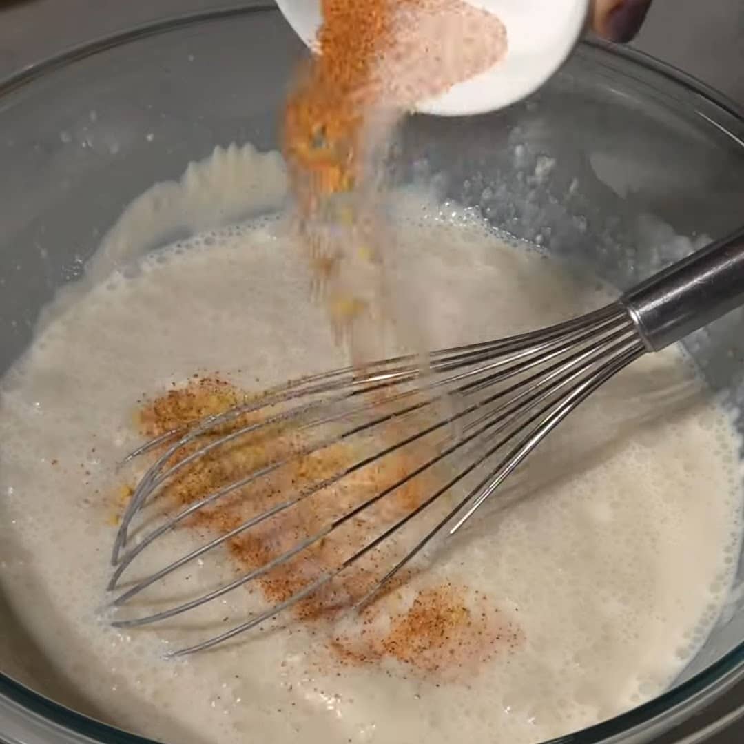 Adding seasonings to southern style mac and cheese.