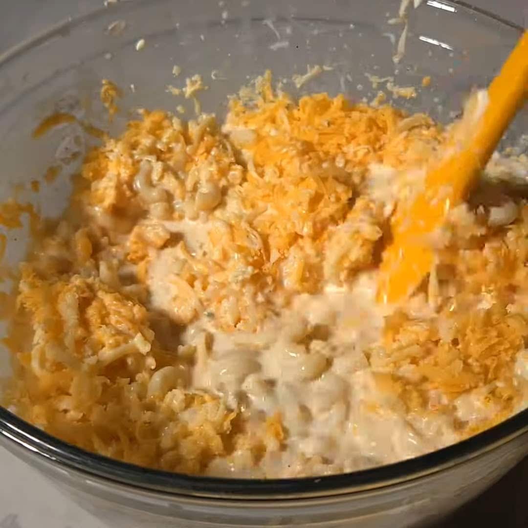 Mixing in cheese for southern baked mac and cheese recipe.