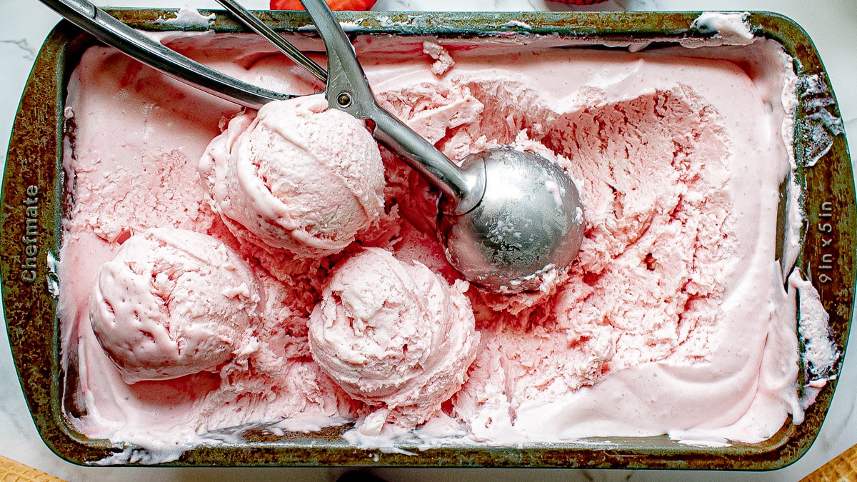 no churn strawberry ice cream in a container with scoops