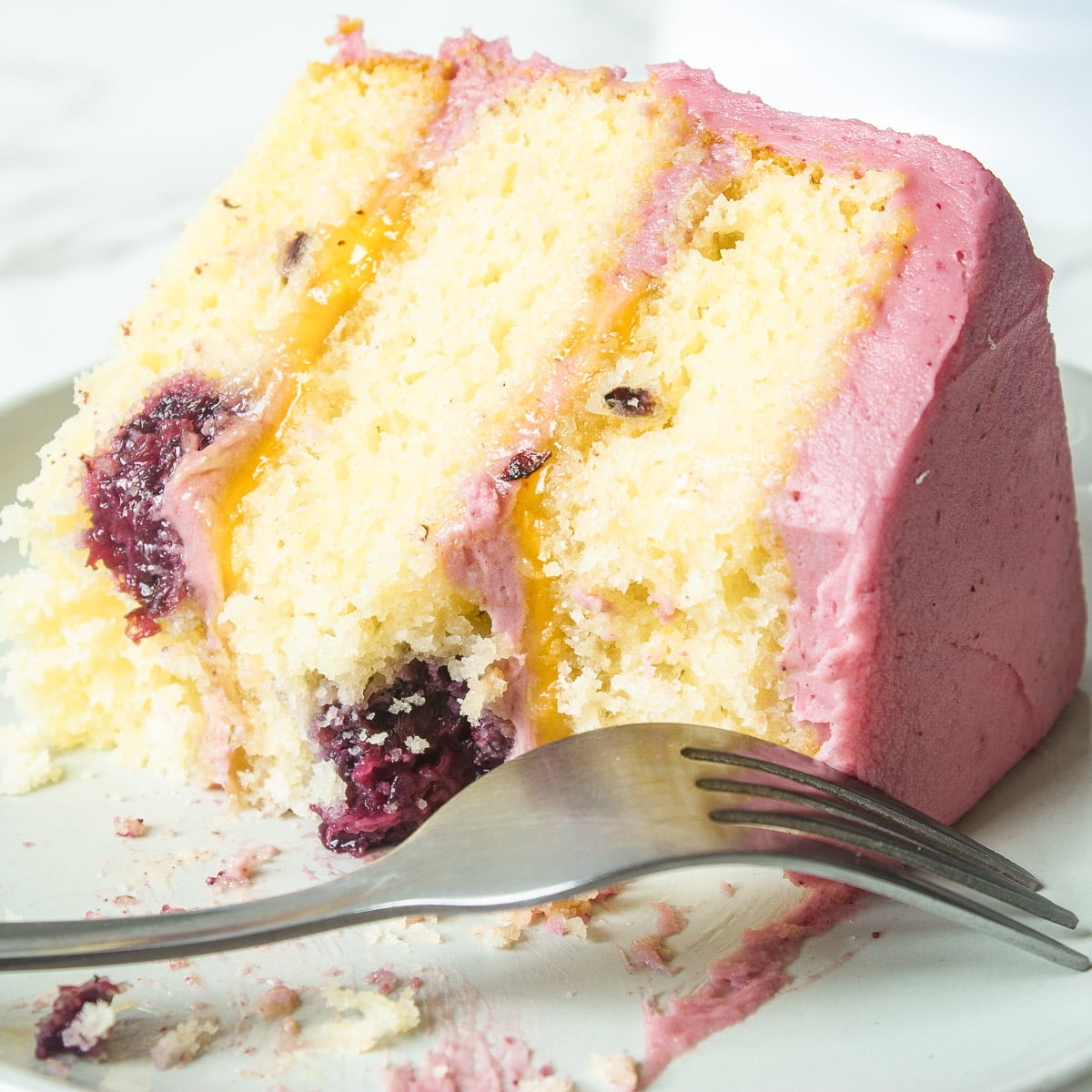 slice of lemon and blackberry cake on a plate with a couple bites taken out