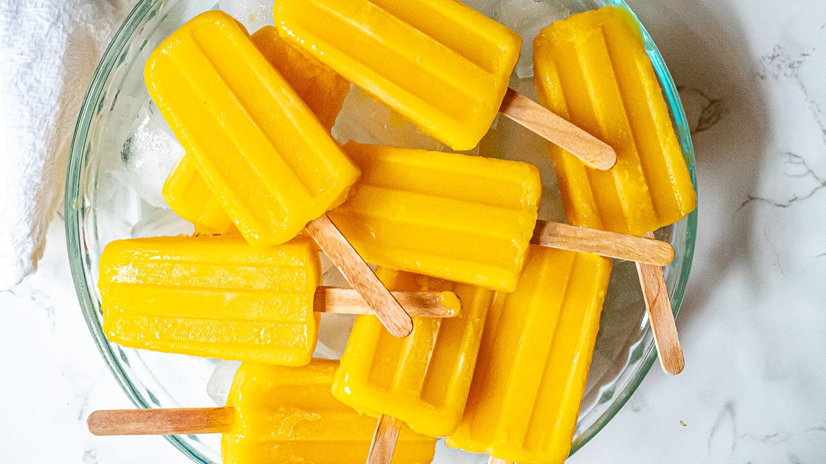 mango popsicles on a tray with ice