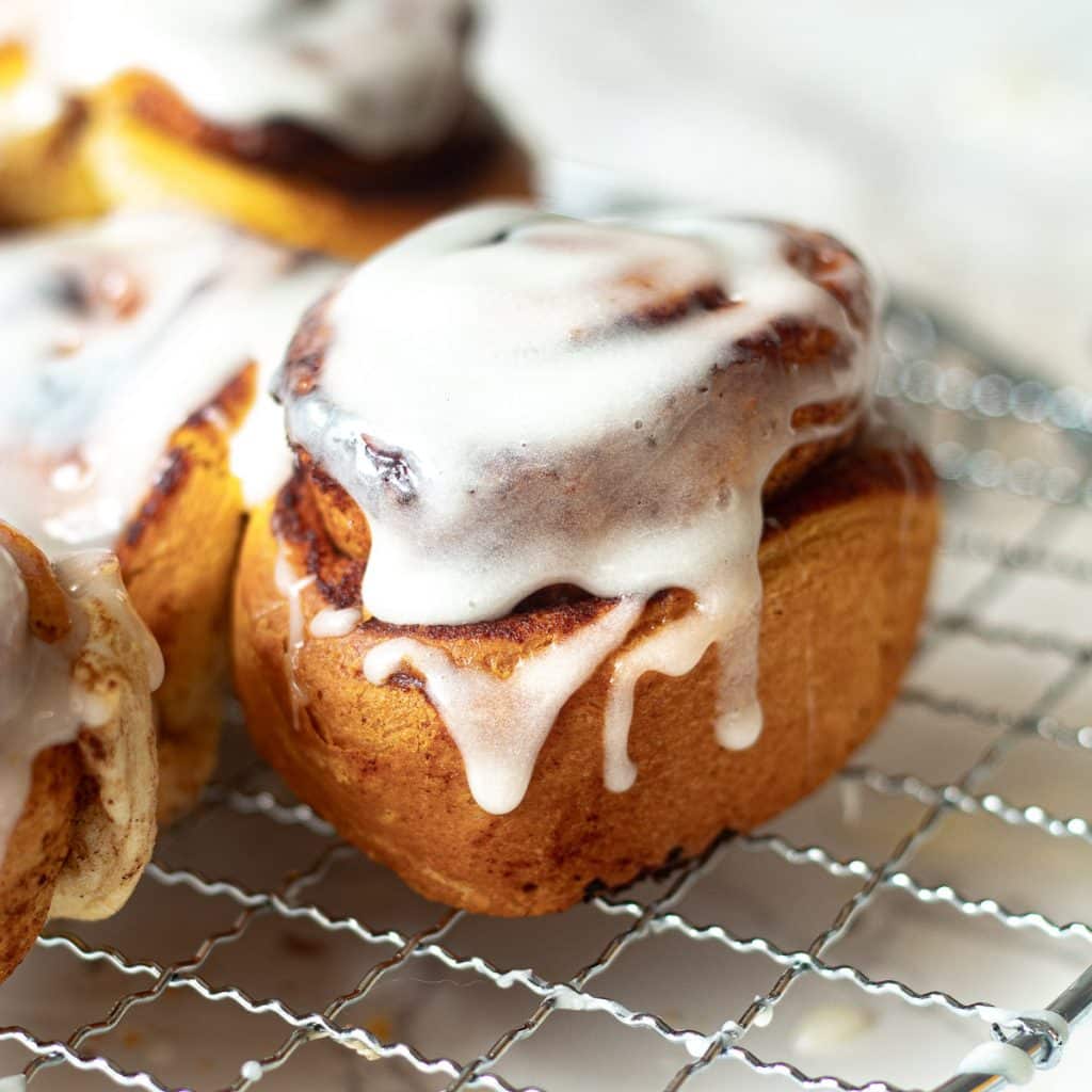 air fryer cinnamon roll topped with icing on a wire rack