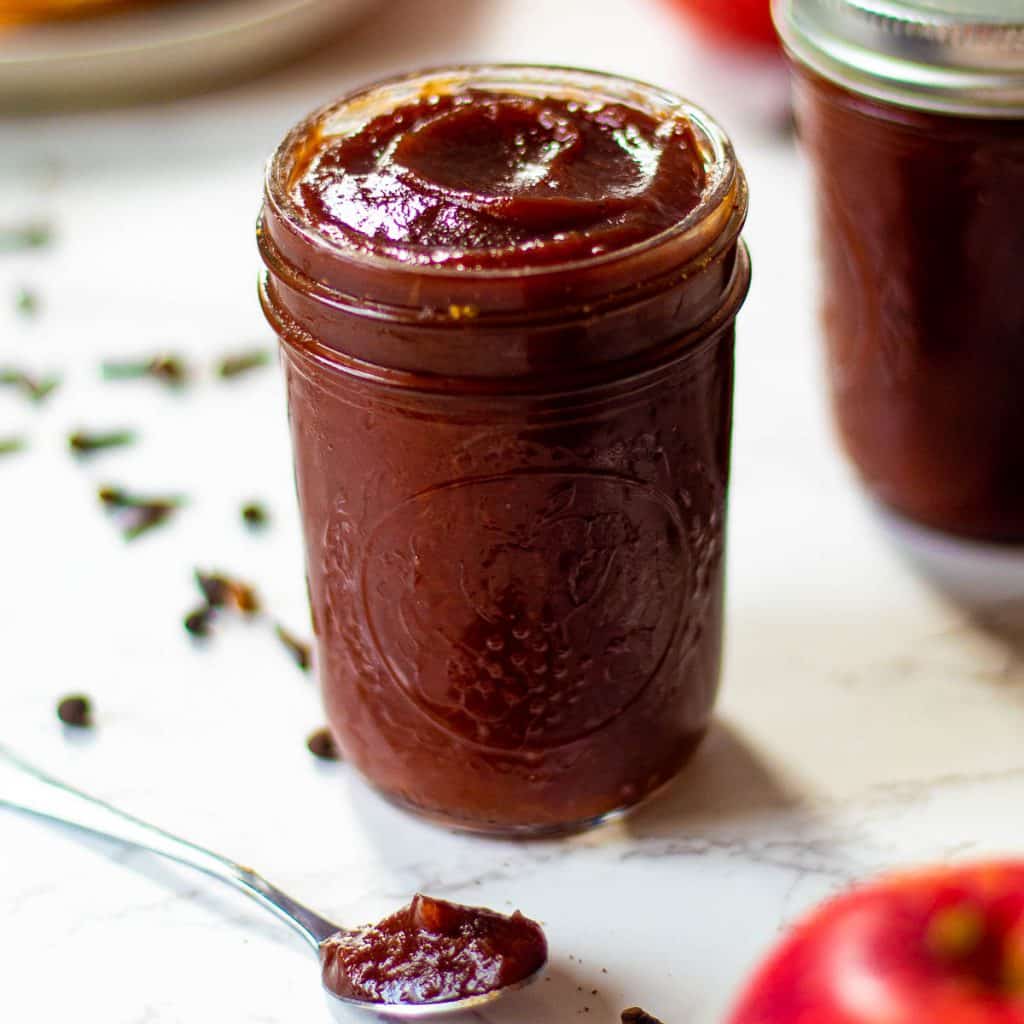 instant pot apple butter in a jar with a spoonful next to it