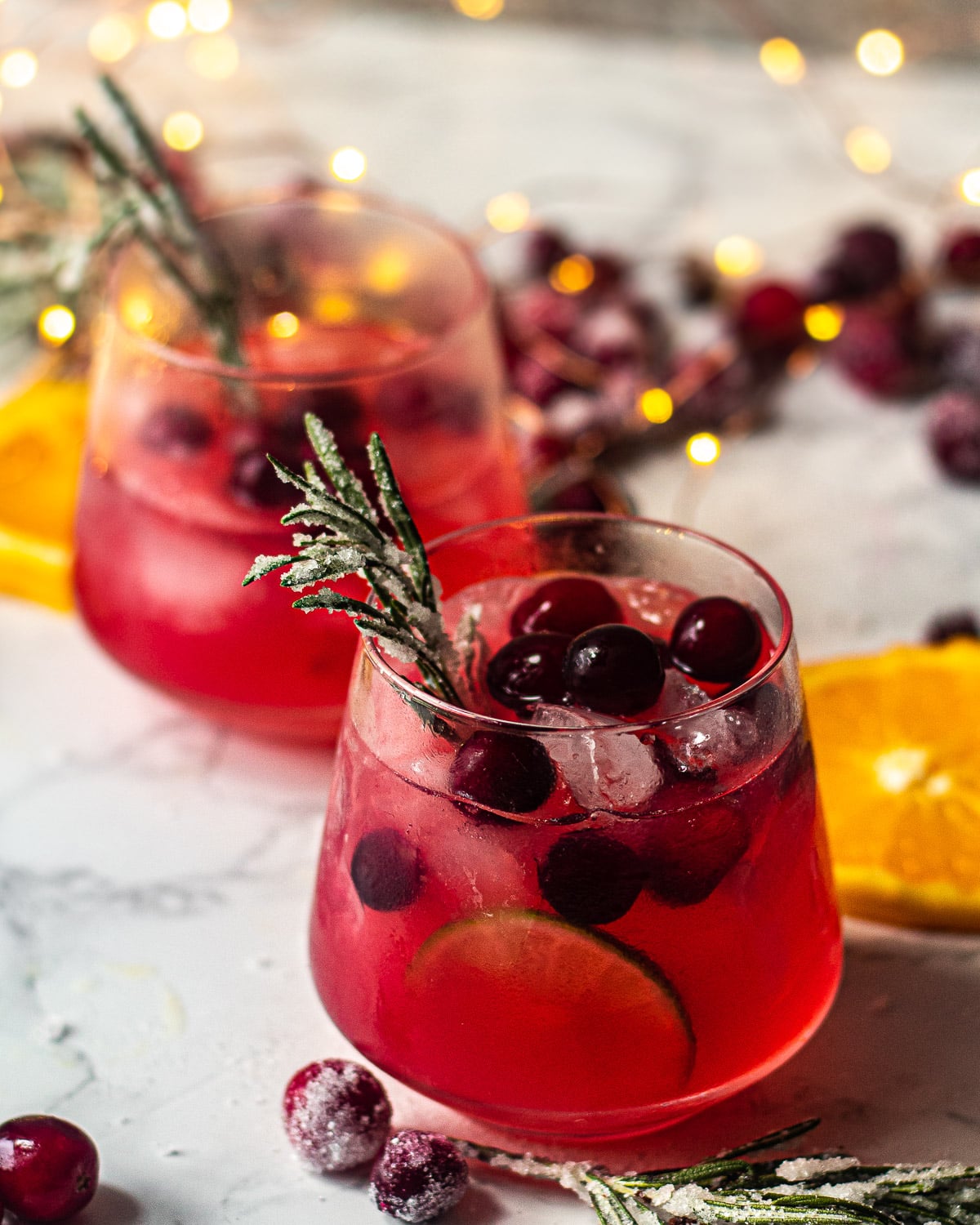 A margarita cocktail with frozen cranberries and sprigs of rosemary.