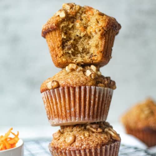 stacked banana carrot muffins, one with a bite taken out