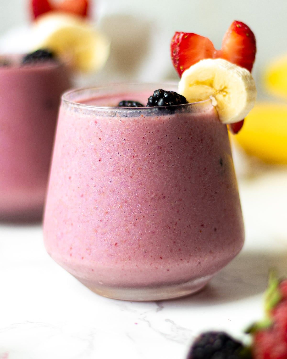 blackberry strawberry banana smoothie in glasses with fruit garnish