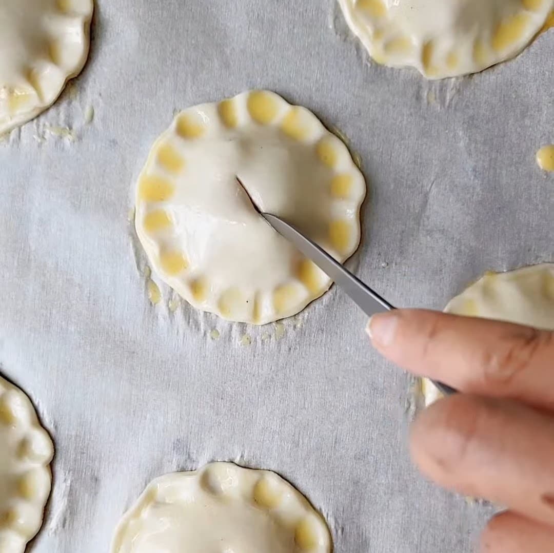 Scoring peach mango pies before baking.