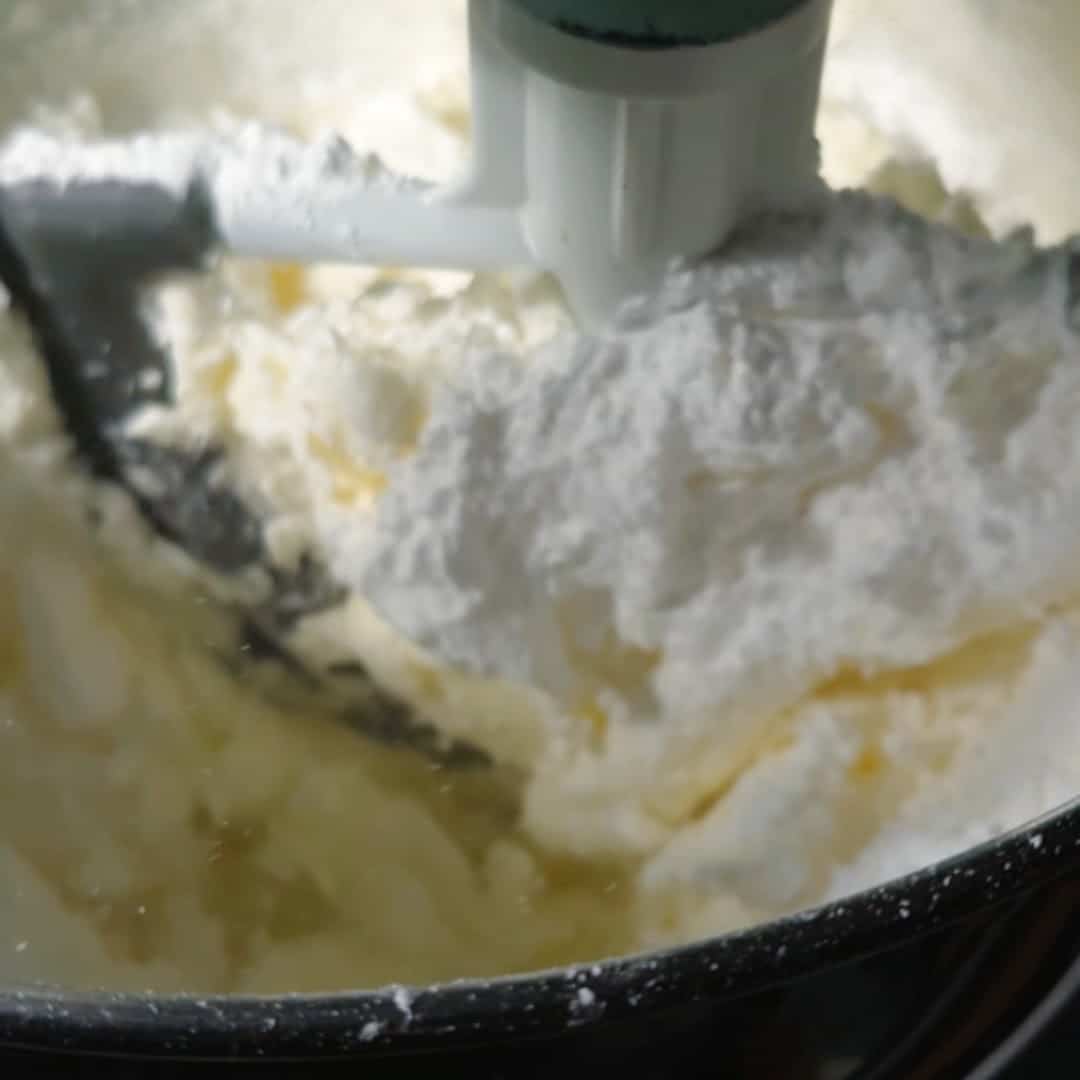 Butter and powdered sugar being whipped together to make a fluffy base for chocolate blueberry cake frosting.