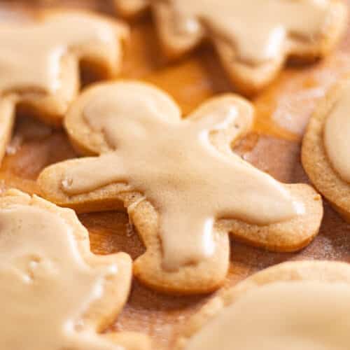 Gingerbread man cut out brown butter sugar cookies cooling on a wooden counter with icing set on top.