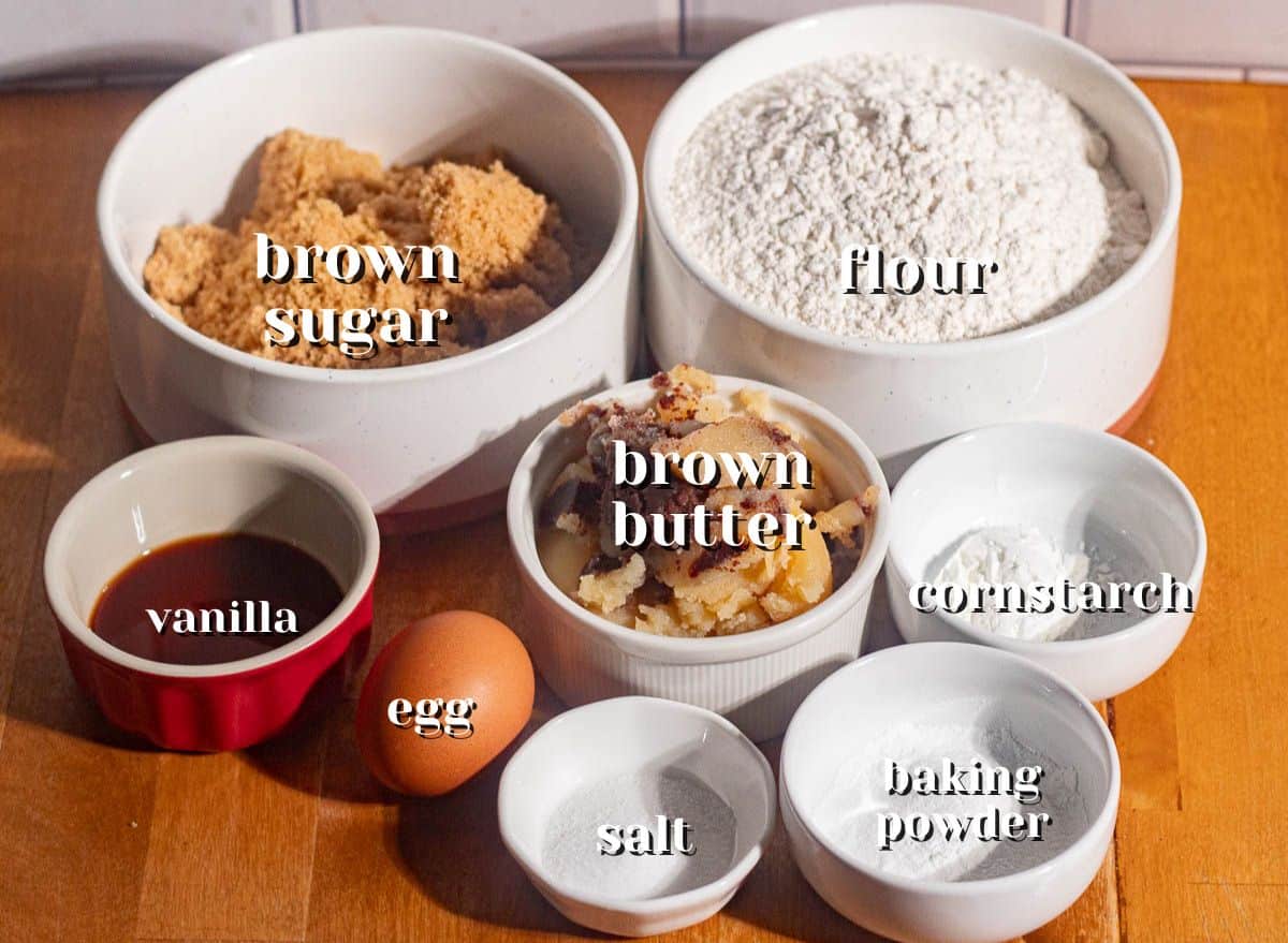 Overhead of ingredients for brown butter sugar cookies, including brown sugar, flour, browned butter, egg, and vanilla.