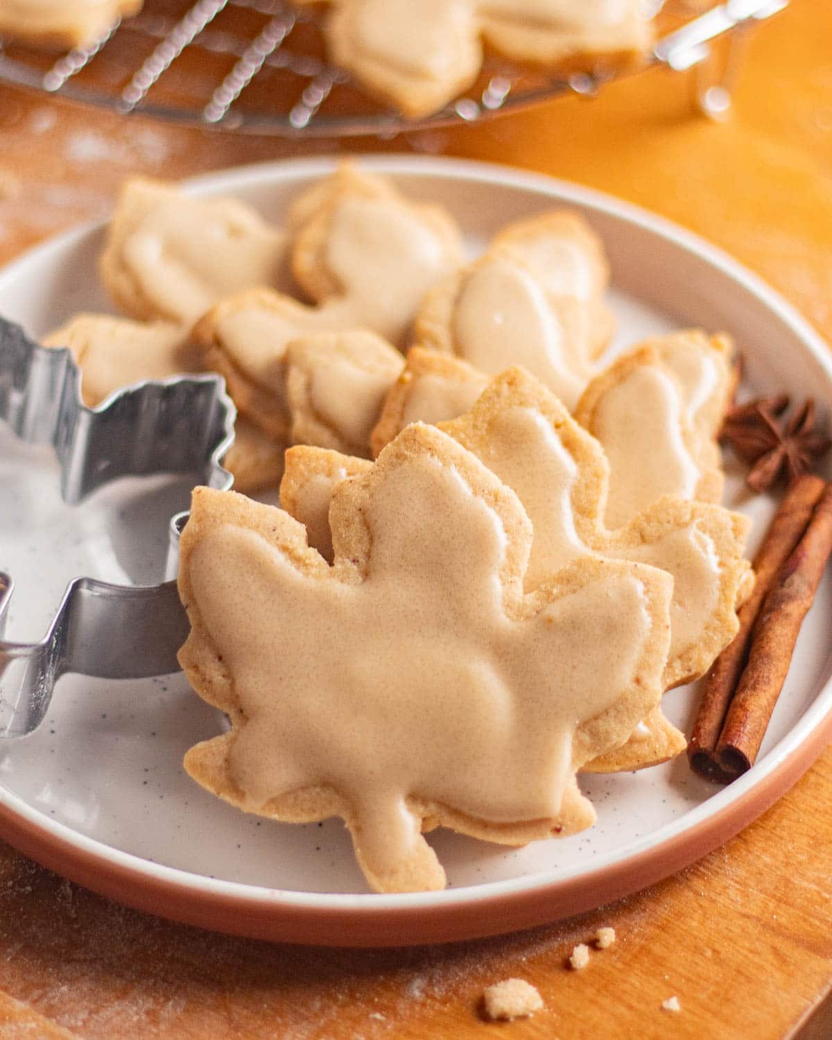 Maple leaf cutout brown butter sugar cookies cooling on a wire rack with icing set on top.