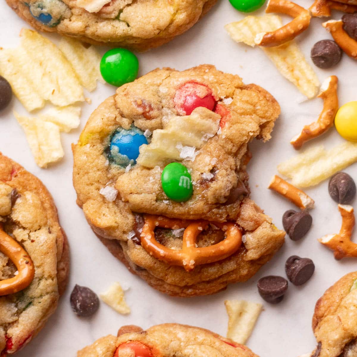 Detailed shot of homemade kitchen sink cookies with pretzels, M&Ms, and potato chips showing gooey centers and crispy edges.