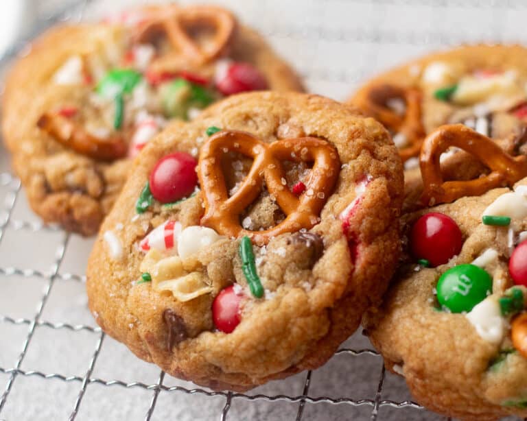 Festive Christmas kitchen sink cookies with red and green M&Ms, pretzels, white chocolate, and sprinkles for holiday cookie trays.