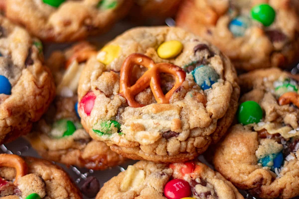 Close-up of chewy kitchen sink cookies loaded with pretzels, chocolate chips, and colorful M&Ms for the best salty-sweet cookie recipe.