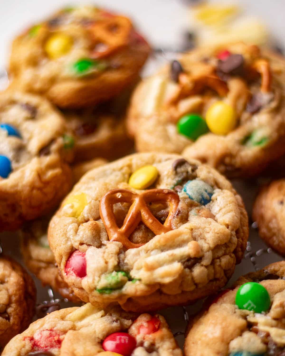 Cooling rack of chewy homemade kitchen sink cookies with pretzels, potato chips, and chocolate candies scattered around.