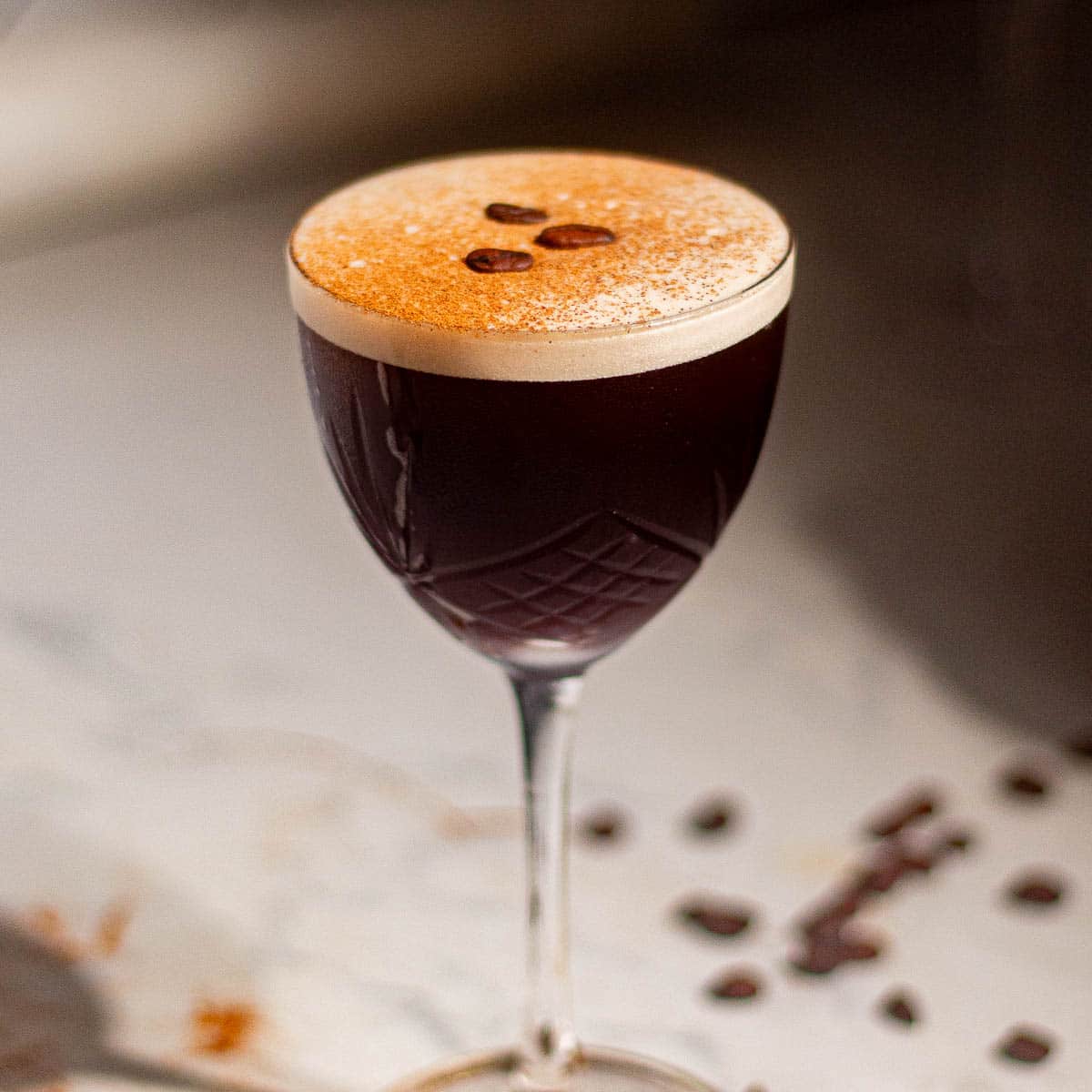 Classic rum espresso martini topped with coffee beans and dusted crema, photographed in elegant glassware.