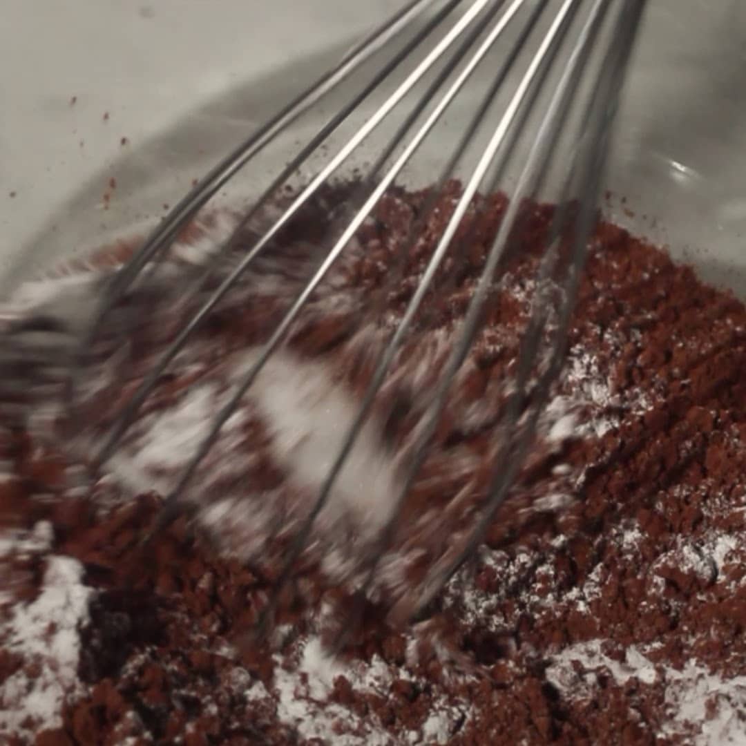 Mixing dry ingredients for the chocolate mousse cake batter in a glass bowl.