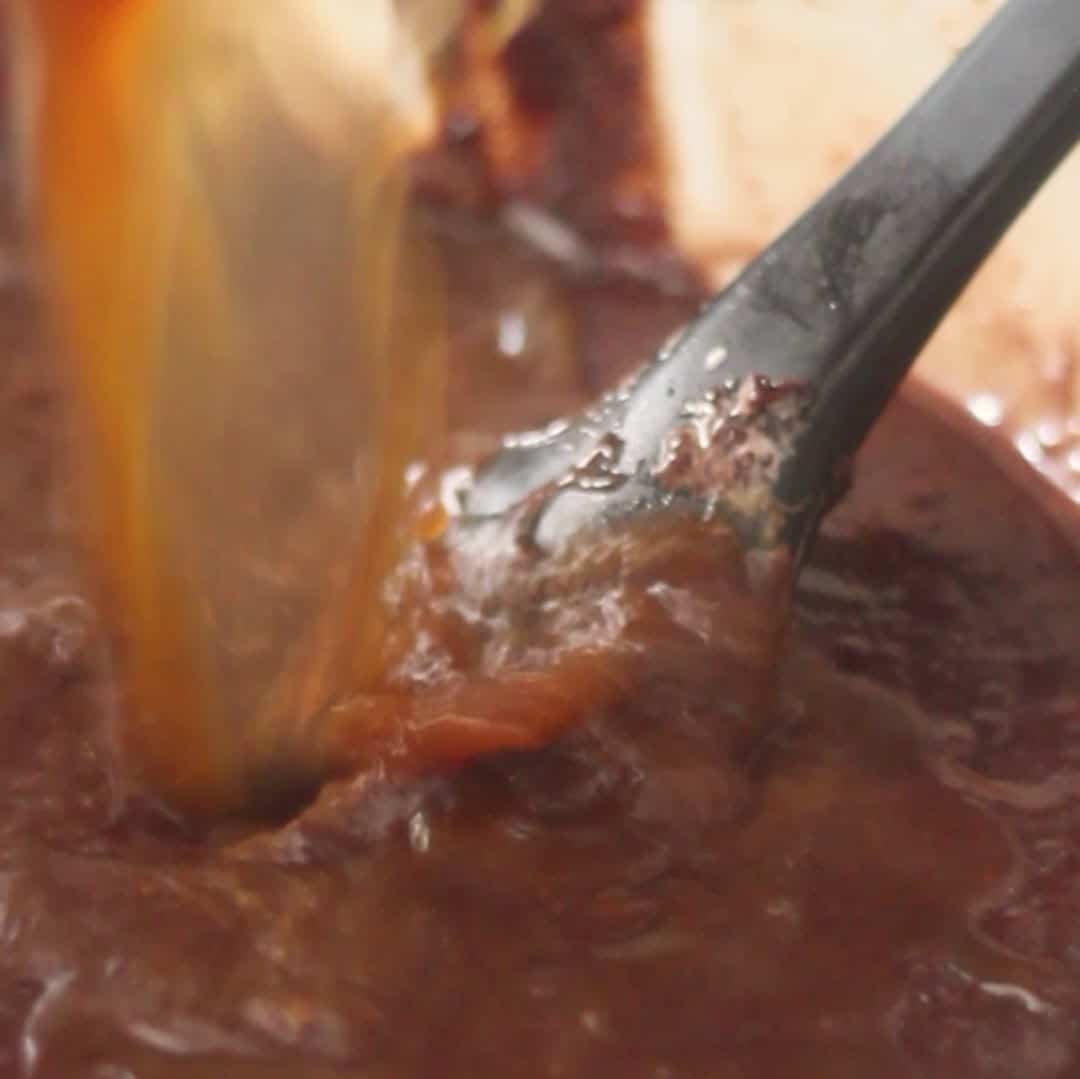 Pouring hot coffee into the cake batter to enhance the flavor of the chocolate mousse cake.