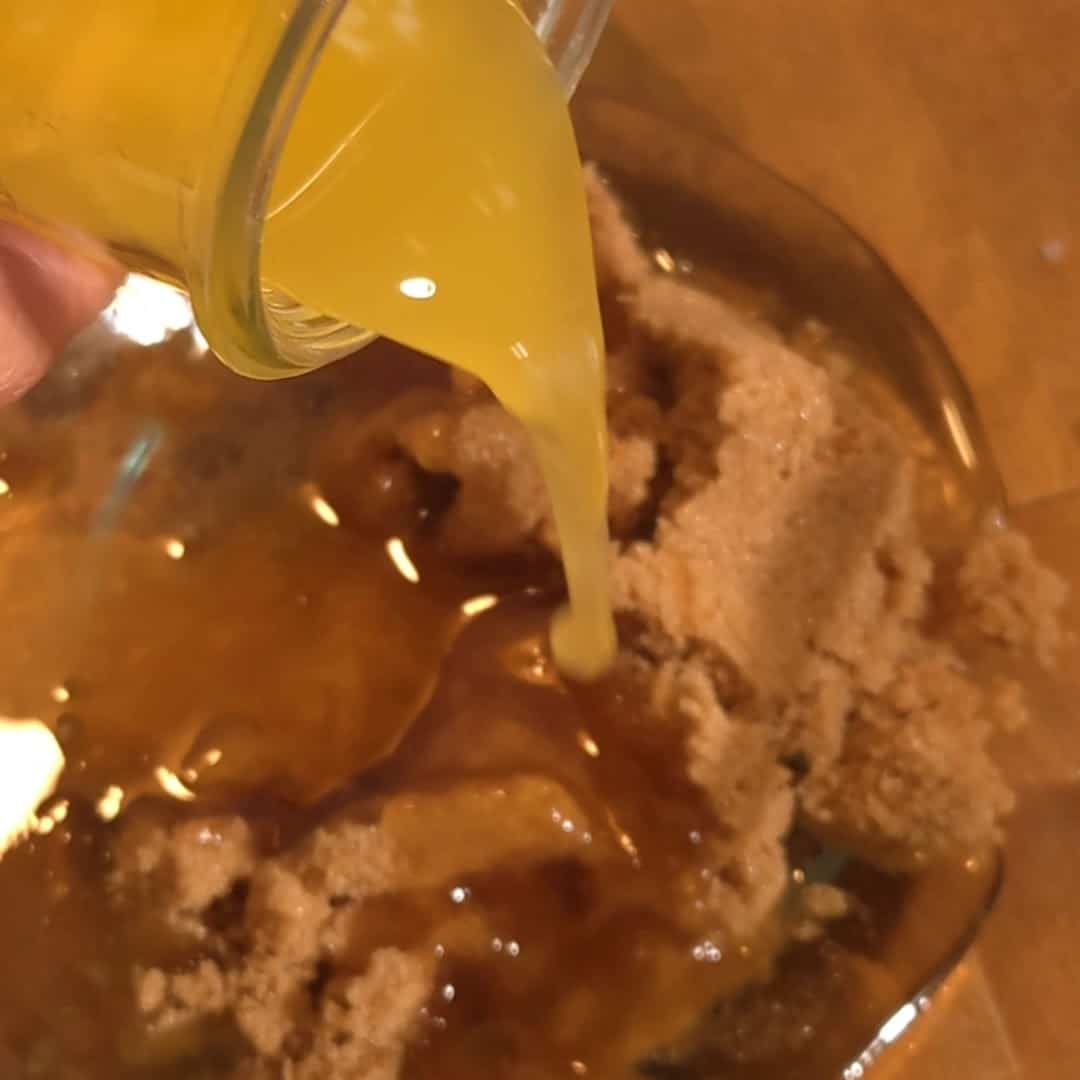 Pouring melted butter over brown sugar to make the rich filling for chocolate chip pecan pie.