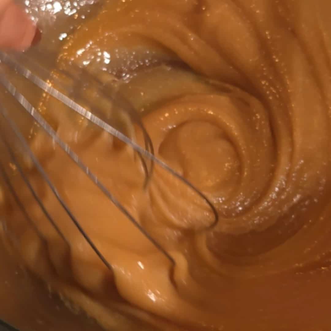 Whisking together brown sugar, butter, and corn syrup to create the smooth filling for chocolate chip pecan pie.