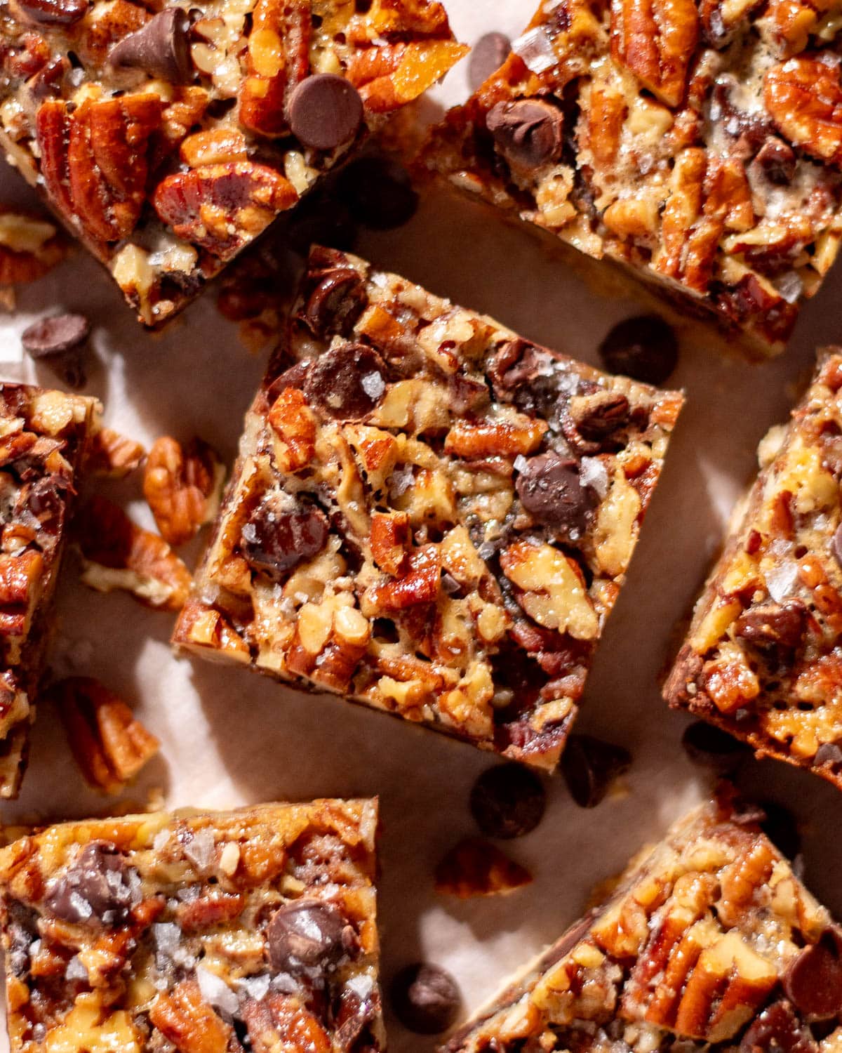 Overhead shot of chocolate and pecan dessert bars with chunks of pecans and melted chocolate chips.