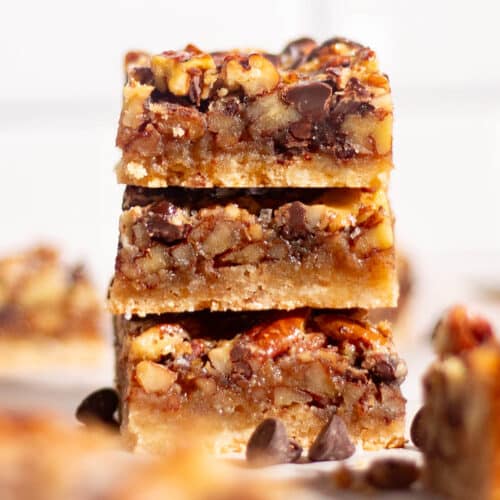 Chocolate pecan pie bars sliced on parchment paper with rich filling and a crisp shortbread crust.