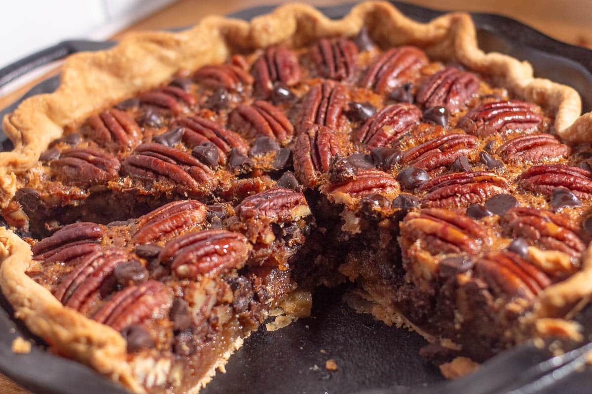 Close-up of pecan pie with chocolate chips recipe, showing melted chocolate and crunchy pecans in buttery crust.
