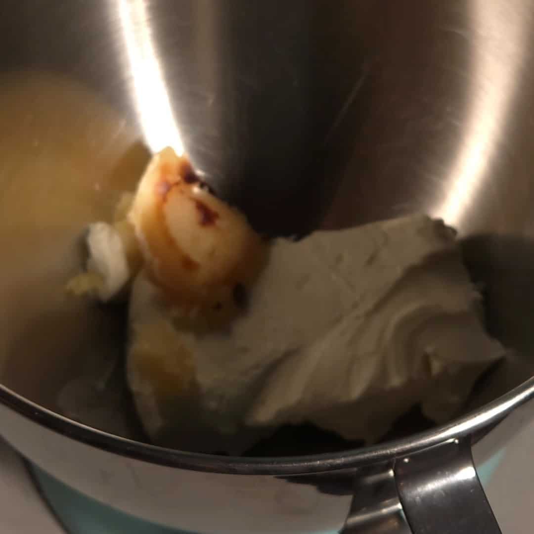 Cream cheese and browned butter in a mixing bowl before whipping into browned butter cream cheese frosting.